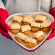 Woman in red gloves holds heart-shaped tin of mini chicken sandwiches